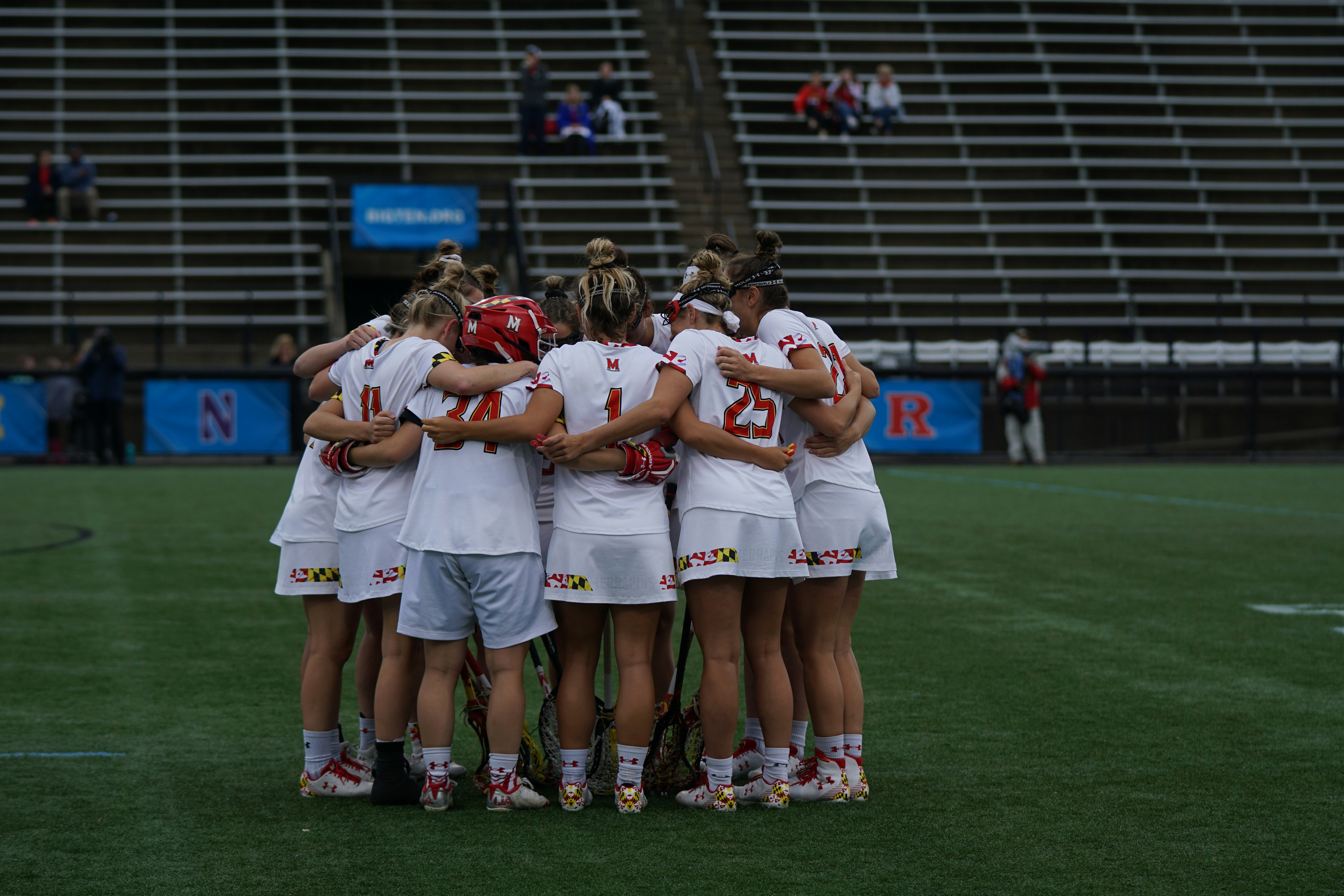 Team of athletes in a tight huddle on a sports field